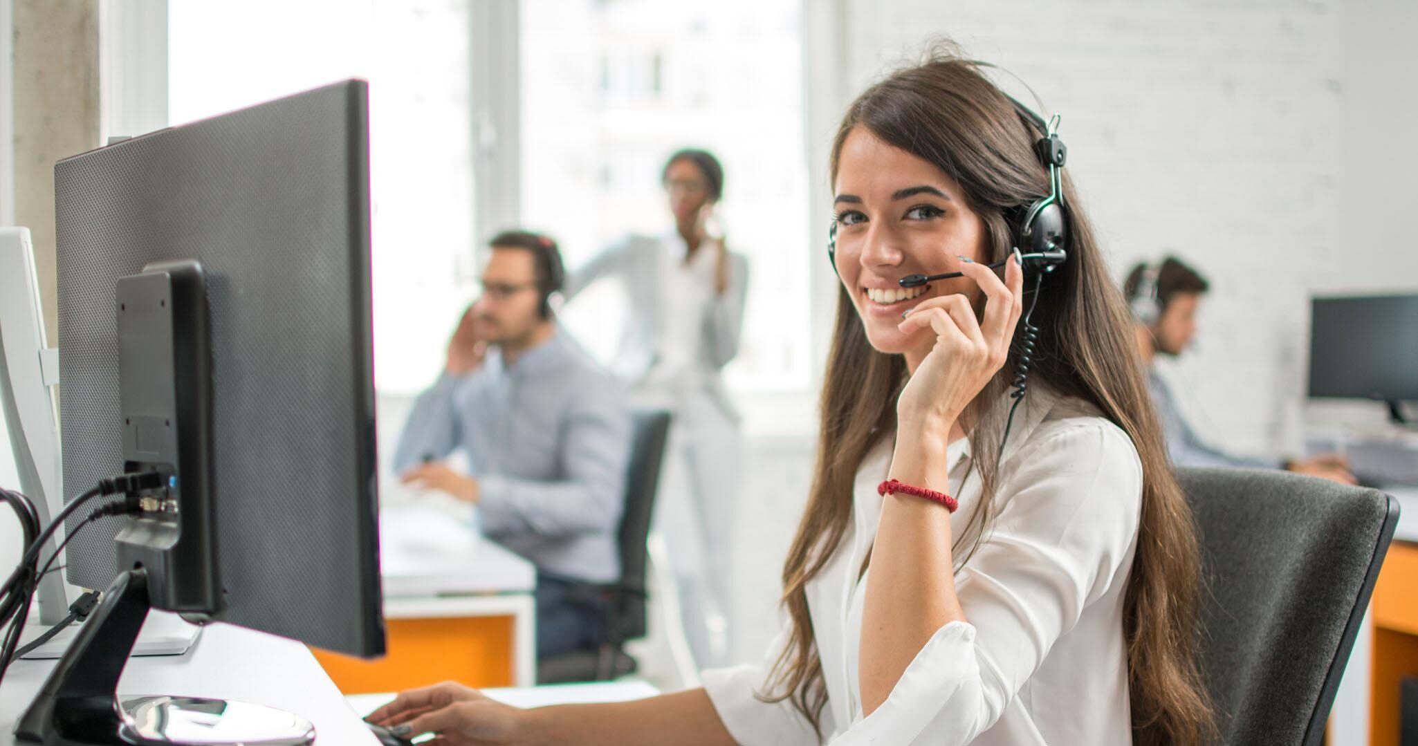 Young friendly operator woman agent with headsets working in a call centre.